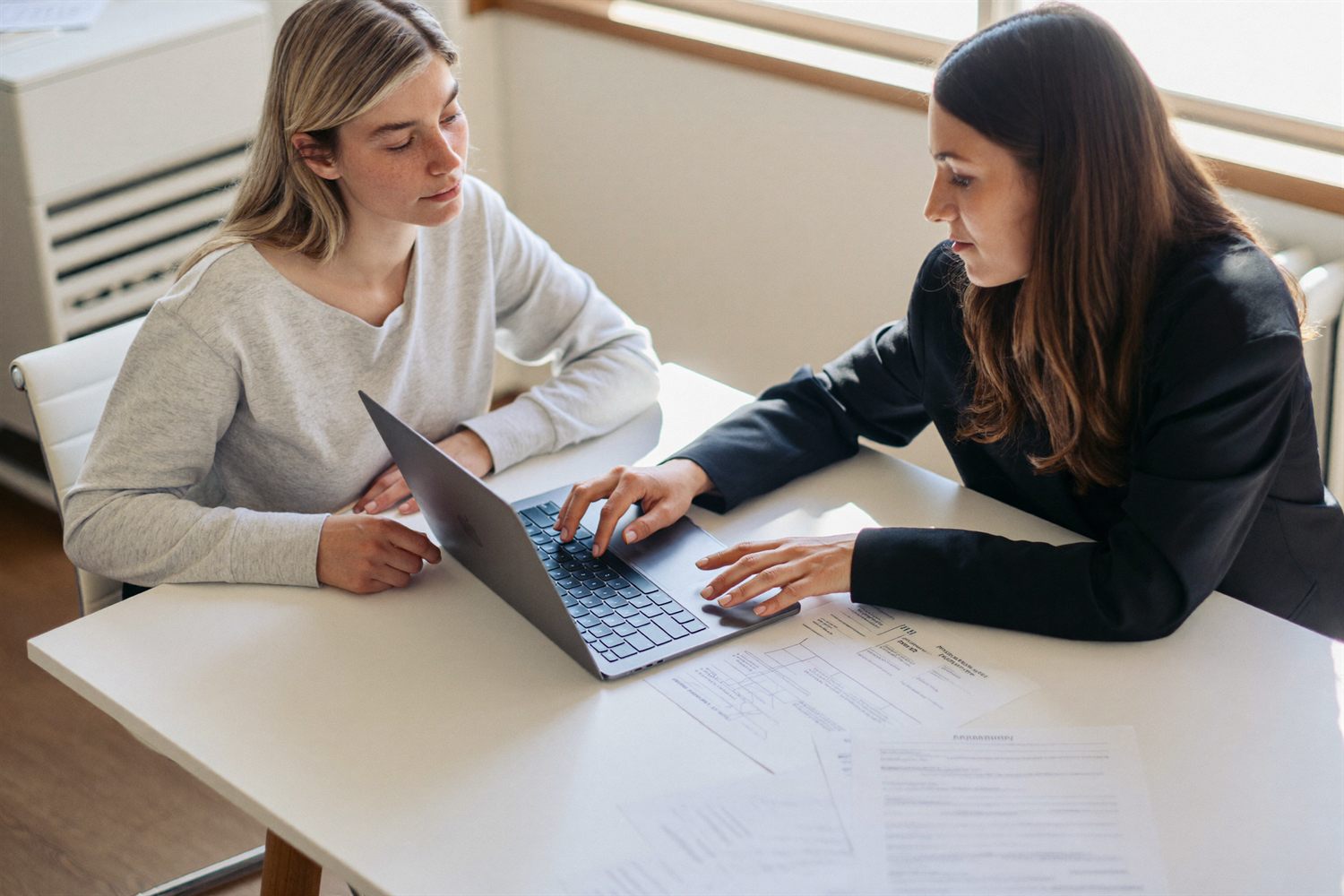 A consultant and a business owner reviewing workflows together on a laptop.