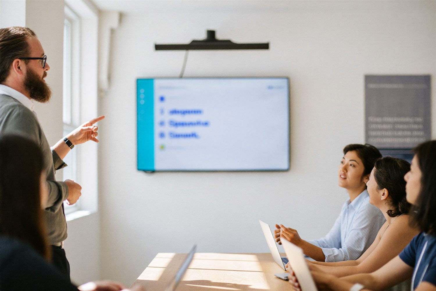 An instructor demonstrating software to a small team seated around a table.